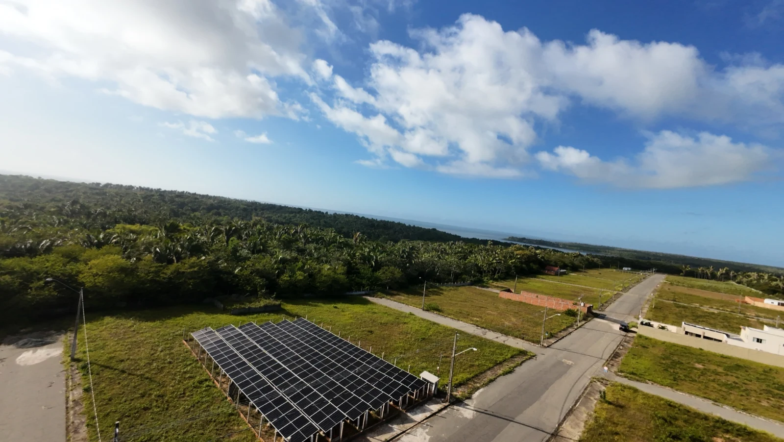 Vista aérea de uma usina solar com painéis próximos a ruas e áreas verdes.